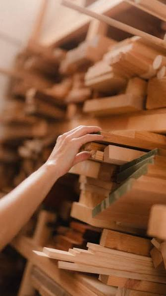 Manos eligiendo madera en el taller